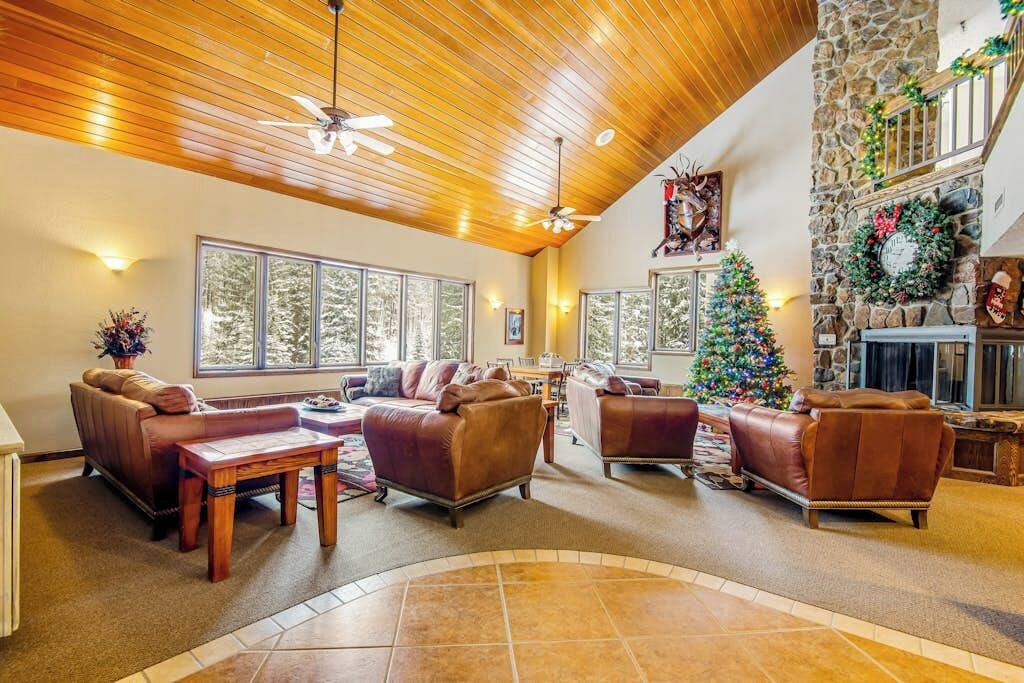 A spacious living area with leather sofas, a wooden coffee table, and a stone fireplace.