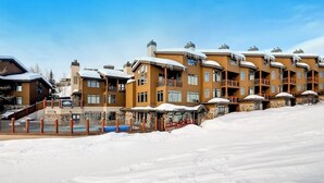 En rad höga byggnader med balkonger, ett poolområde och ett snötäckt landskap.