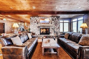 Eine gemütliche Lobby mit Ledersofas, einem Kamin aus Stein und einer Holzbalkendecke.