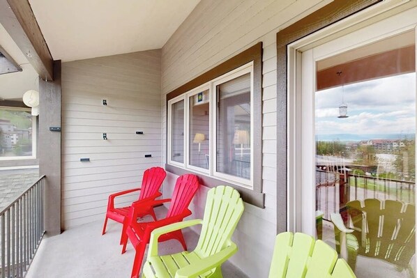 A balcony with Adirondack chairs, a railing, and a view of the cityscape. - Luxury home one block from gondola w/mountain views, free WiFi, & private W/D (Steamboat Springs)