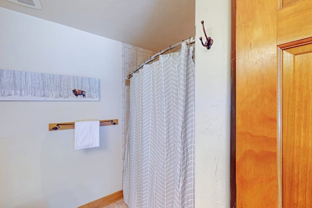 Een badkamer met een douchegordijn, een handdoekrek met een handdoek en een aan de muur bevestigd handdoekrek.