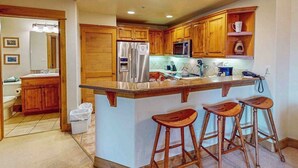 Une cuisine avec des meubles en bois, un réfrigérateur en acier inoxydable, un four à micro-ondes et un grand îlot central doté de tabourets de bar.