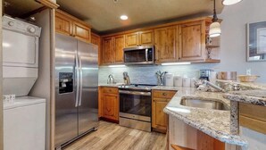 A kitchen with wooden cabinets, stainless steel appliances, granite countertops, and a built-in oven. - EagleRidge Lodge 209 Inviting, walk-to-lift condo w/ fireplace & shared pool/hot tubs/gym/shuttle (Steamboat Springs)