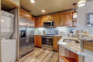 Eine Küche mit Holzschränken, Edelstahlgeräten, Granit Arbeitsplatten und einem eingebauten Backofen.