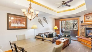 Un salon chaleureux avec une cheminée, un coin repas et un ventilateur de plafond.