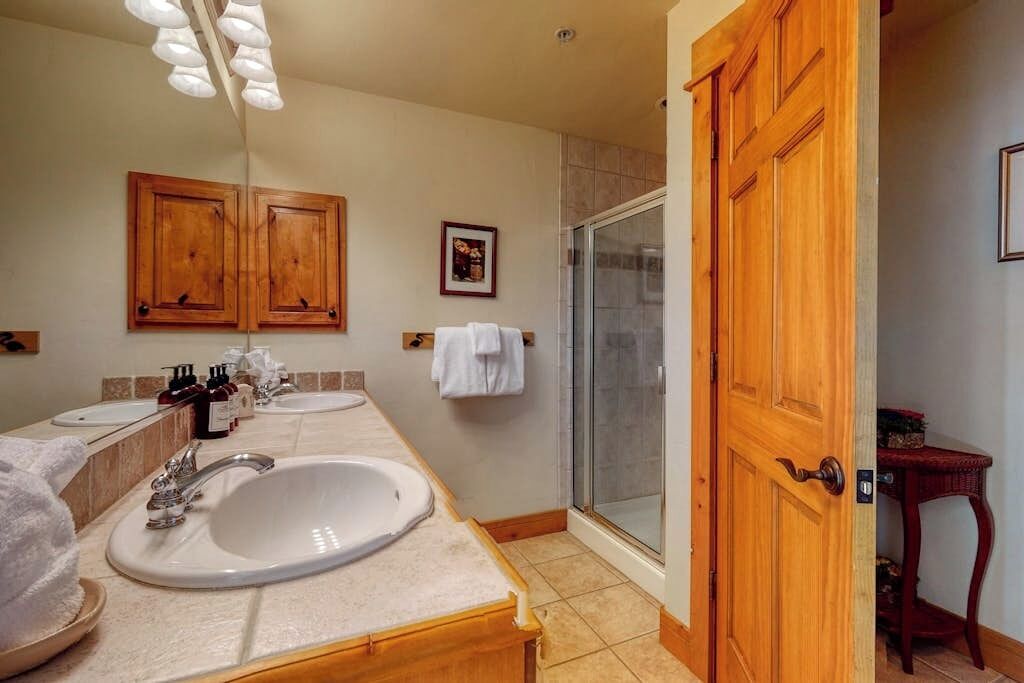 Un bagno con due lavandini, una doccia, mobili in legno e un portasciugamani.