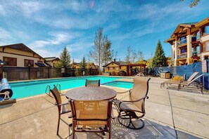 Ein Poolbereich mit Tisch und Stühlen, umgeben von Gebäuden.