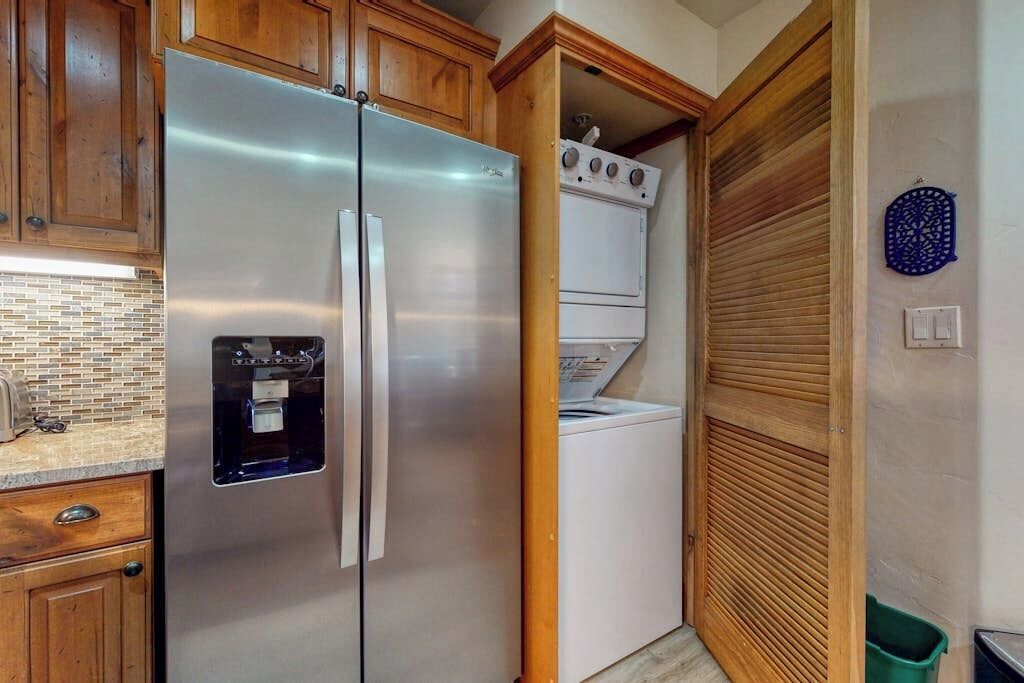Cozinha com geladeira de aço inoxidável, forno embutido e máquina de lavar.