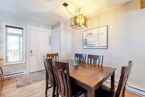 A dining area with a wooden table and chairs, a chandelier, and a framed picture on the wall. - Updated, Top-Floor Condo w/ Gas Fireplace, Shared Pool/Hot Tub - Walk to Shuttle (Steamboat Springs)