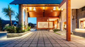 A hotel entrance with a covered walkway, a stone facade, and a well-lit interior. - Ashva Swiss-Belresort, Ubud (Ubud)