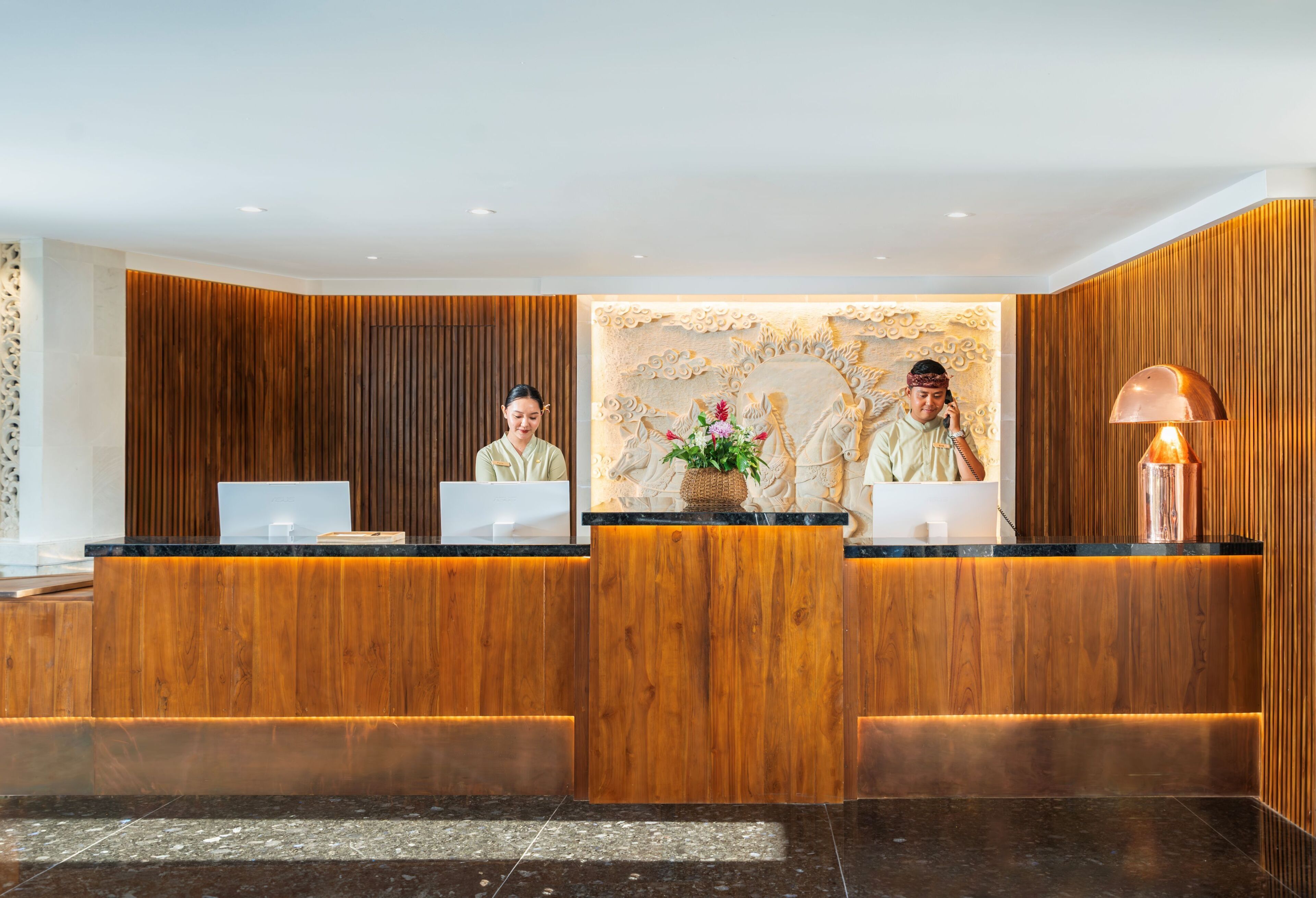A reception desk with three counters, a decorative wall, and a lamp.