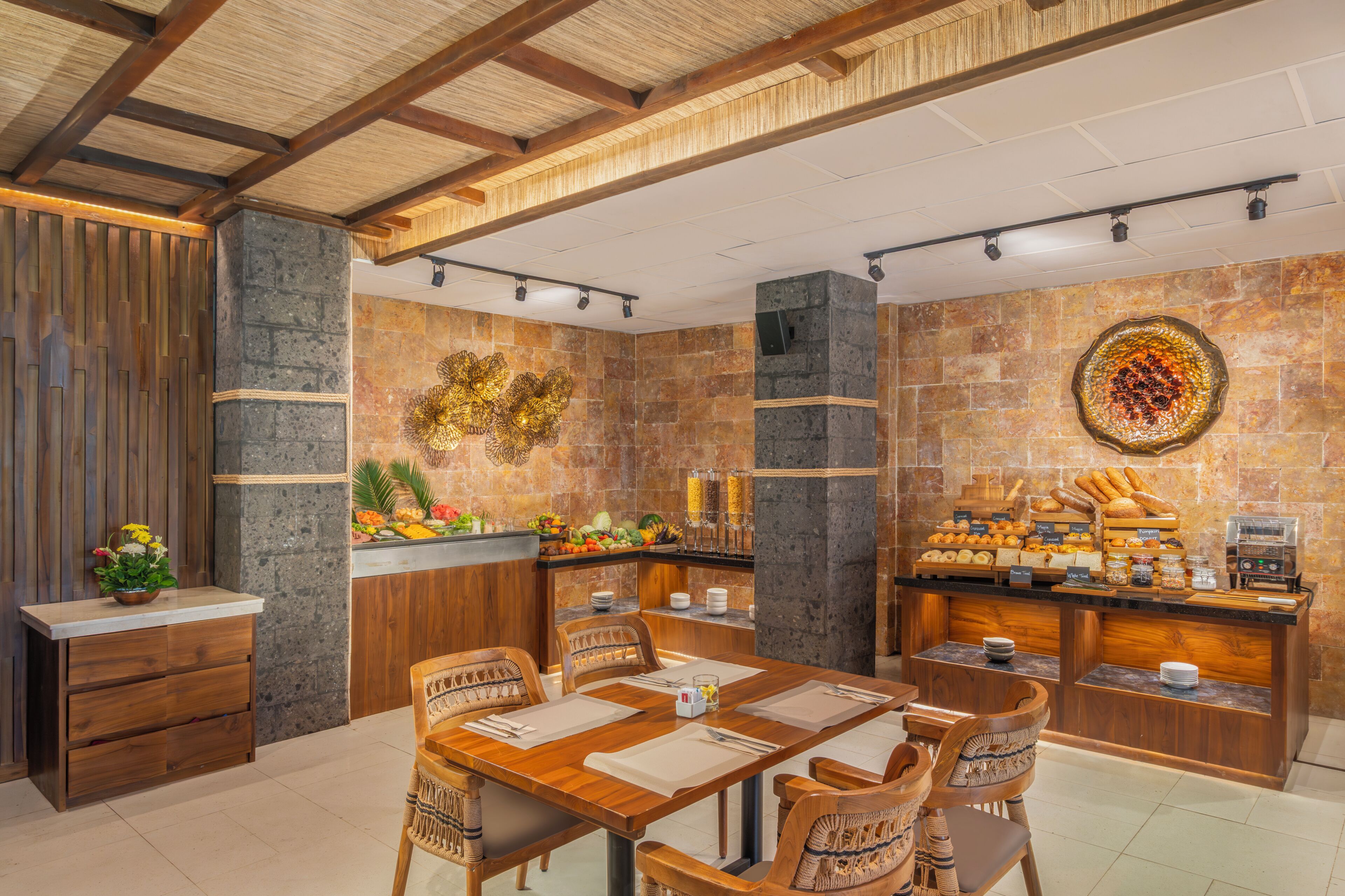 Un restaurant avec un mur en pierre, un plafond en bois et un buffet proposant une variété de plats.