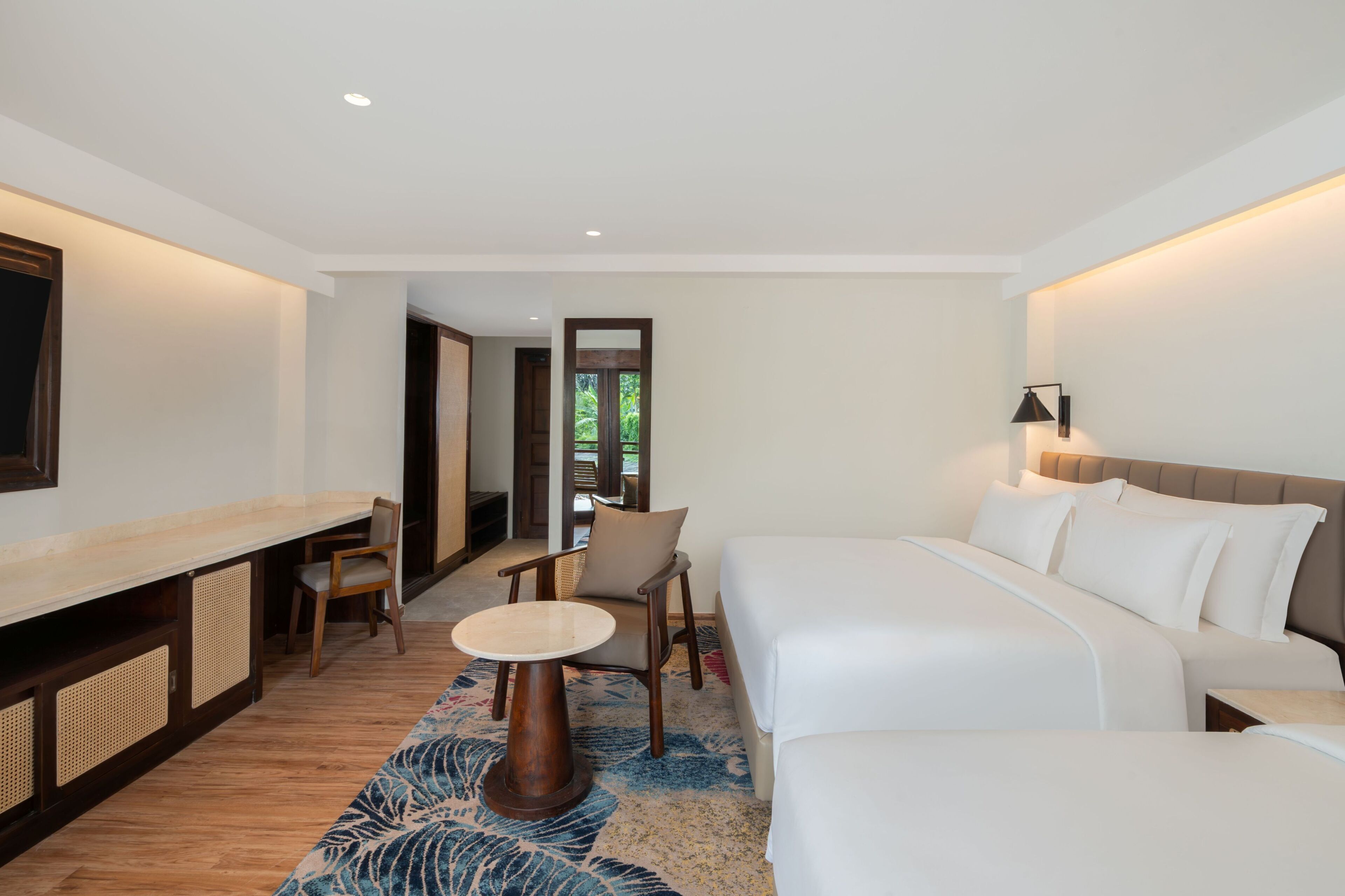 A hotel room with a bed, a desk, a chair, and a small table.