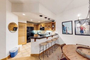 Eine Küche mit Holzschränken, einem schwarzen Kühlschrank und einer Bar mit Barhocker.