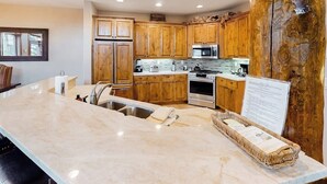 A kitchen with wooden cabinets, a large island, stainless steel appliances, and a stone countertop. - 1410 EagleRidge Multi-level townhome with AC, fireplace, pool & hot tubs - walk to the gondola (Steamboat Springs)