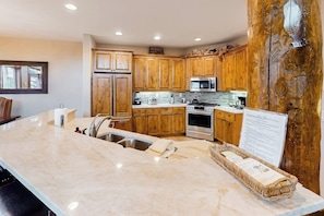 A kitchen with wooden cabinets, a large island, stainless steel appliances, and a stone countertop. - Multi-level townhome with AC, fireplace, pool & hot tubs - walk to the gondola (Steamboat Springs)