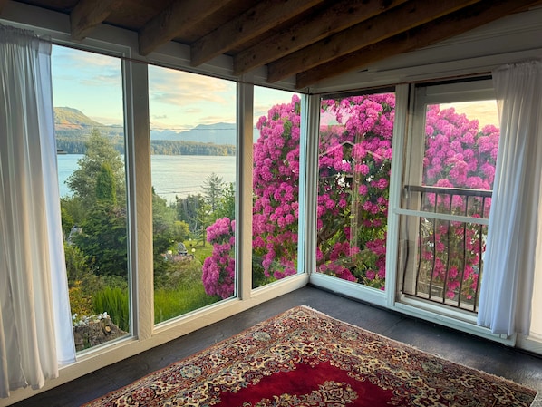 Una habitación con ventanas amplias, un tapete estampado y vistas a un lago y montañas.
