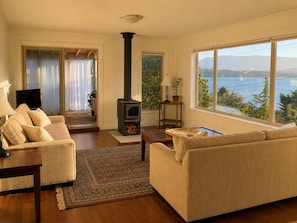 Una sala de estar con sofá, televisión, chimenea y vista al agua.