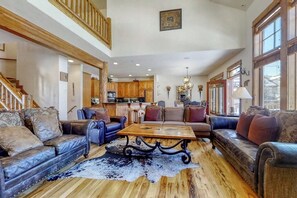 Ein großzügiges Wohnzimmer mit Ledersofas, einem Couchtisch und einem rustikalen Holzboden.