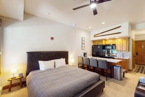A hotel room with a bed, a desk, a kitchenette, and a ceiling fan. - Walk-to-gondola studio with hot tubs, pool, fitness room, and ski shuttle (Steamboat Springs)