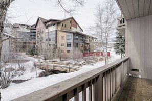 A multi-story building with a wooden deck and snow-covered surroundings. - Pretty & bright townhome in a great location for skiing w/ shared hot tubs (Steamboat Springs)