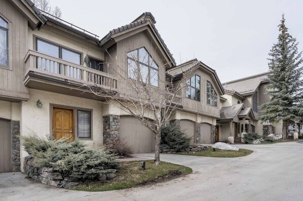 A residential building with a stone facade, a wooden front door, and a balcony. - Pretty & bright townhome in a great location for skiing w/ shared hot tubs (Steamboat Springs)