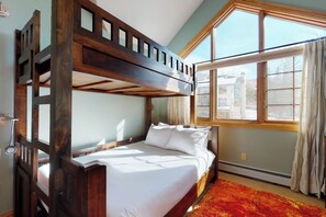 A bunk bed room with a large window, a wooden headboard, and a red carpet. - Pretty & bright townhome in a great location for skiing w/ shared hot tubs (Steamboat Springs)