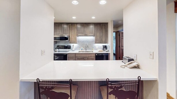 A modern kitchen with a central island, wooden cabinets, and built-in appliances. - Timber Run 313 - Lovable condo with pool, hot tubs, sauna & clubhouse (Steamboat Springs)