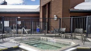 A swimming pool with a 3 FT depth limit, surrounded by a metal fence, with outdoor seating and a building in the background. - Timber Run 313 - Lovable condo with pool, hot tubs, sauna & clubhouse (Steamboat Springs)