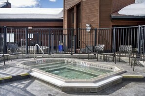 Ein Pool mit einer maximalen Tiefe von 3 Fuß, umgeben von einem Metallzaun, mit Sitzgelegenheiten im Freien und einem Gebäude im Hintergrund.