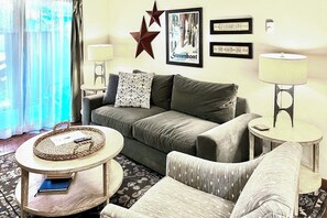 Ein Wohnzimmer mit einer Couch, zwei Beistelltischen, einem Couchtisch und einem gemusterten Zierkissen.