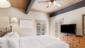 Une chambre à coucher avec un lit, une télévision, une commode et un ventilateur de plafond.