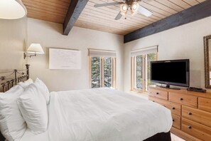 Ein Schlafzimmer mit einem Bett, einem Fernseher, einem Schminktisch und einem Deckenventilator.