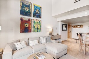 Ein Wohnzimmer mit einem Ecksofa, einem Couchtisch und vier Bildern mit Bärenmotiven an der Wand.