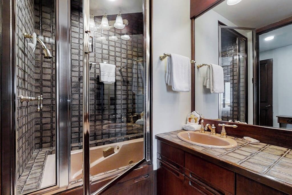 A bathroom with a glass-enclosed shower, a sink with a mirror, and a towel rack.