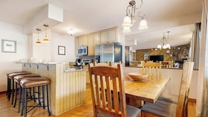 Een moderne keuken met houten kastjes, een centraal eiland, barkrukken en hanglampen.