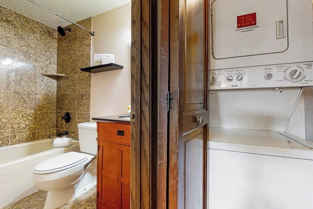 A bathroom with a toilet, a shower, and a washing machine.