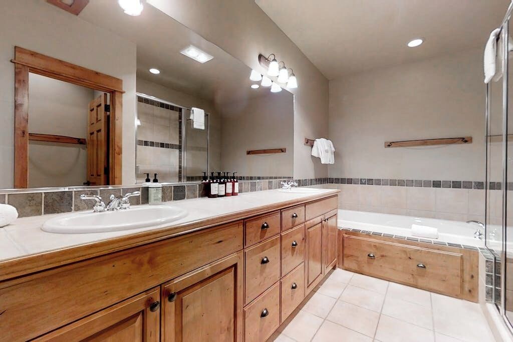 A modern bathroom with a large vanity, a bathtub, and a glass shower enclosure.