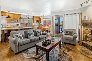 Ein Wohnzimmer mit Sofa, Sessel, Couchtisch und Kamin.