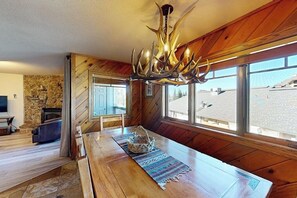 Ein Holzkamin mit einem großen Esstisch, einem Kronleuchter und einer Steinwand.