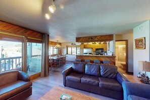 Ein geräumiger Wohnbereich mit Ledersofa, Holztisch und einer Küchenzeile mit Bar.