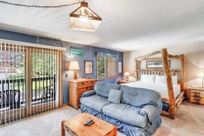 Un dormitorio con cama, sofá, cómoda, lámpara y un cartel en la pared.