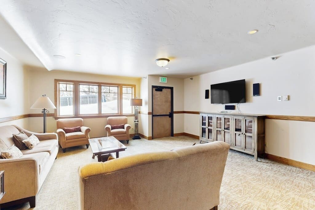 A hotel lobby with a sofa, armchairs, a coffee table, a TV, and a cabinet.