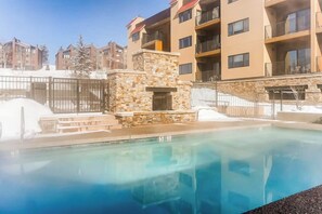 Ein Pool mit einer Steinstruktur, umgeben von mehrstöckigen Gebäuden mit Balkonen.
