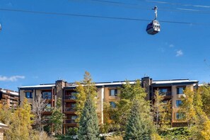 Ein mehrstöckiges Gebäude mit Balkonen, einer Seilbahn und umliegenden Bäumen.