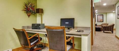 A conference room with two office chairs, a desk with a computer, and a decorative plant.