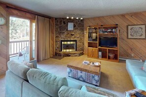 Ein gemütliches Wohnzimmer mit Kamin, Bücherregal, Fernseher und einer Couch.