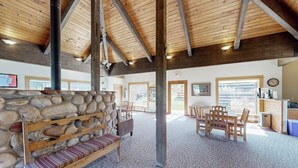 Un vestíbulo amplio con pared de piedra, bancos de madera, un mostrador de recepción y vistas al exterior.