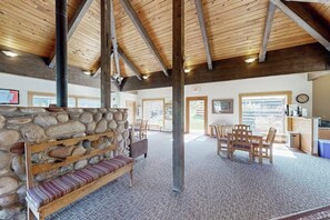 Eine geräumige Lobby mit Steinwand, hölzernen Bänken, einem Empfangstresen und Blick ins Freie.
