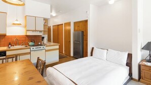 Ein kleines Hotelzimmer mit Bett, einer Kochnische, einem Essbereich und einem Badezimmer.